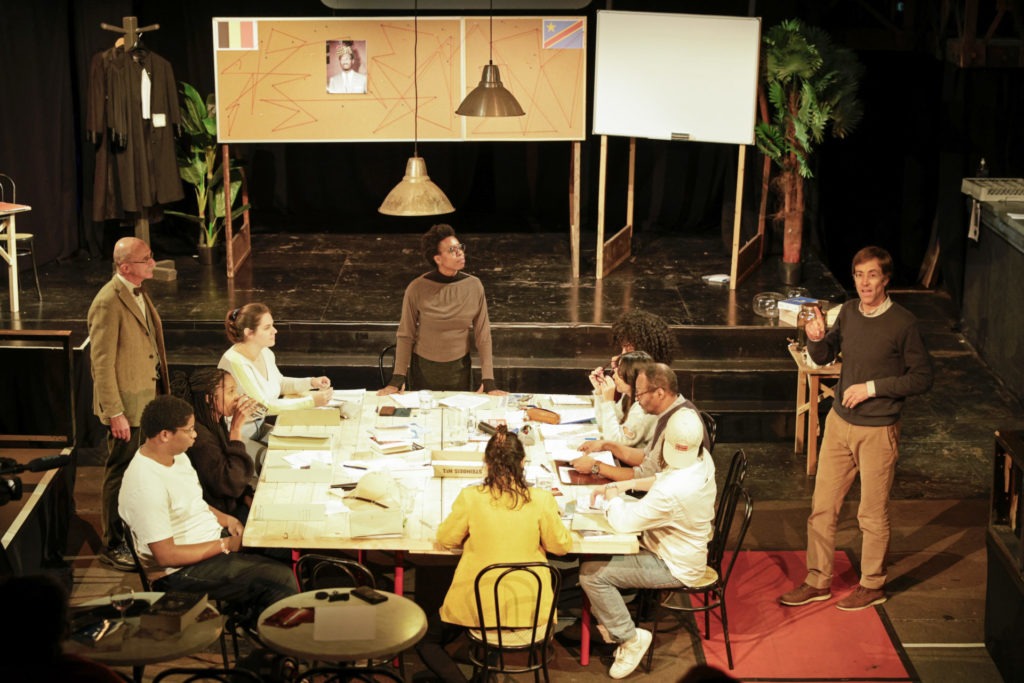 Qui a tué Patrice Lumumba ? est une pièce de théâtre qui met en scène un jury d’assises fictif chargé de faire le point sur les responsabilités dans l’assassinat de Patrice Lumumba. Et aborder cette question juridique est une opportunité pour raconter et questionner l’Histoire coloniale de la Belgique au Congo. C’est un projet artistique et pédagogique qui s’inscrit au cœur du travail de la Clinique juridique Rosa Parks pour les droits humains. Ce sont ainsi les étudiant·es de Master en droit de l’UCLouvain qui ont réalisé les recherches nécessaires à l’écriture du texte théâtral et ce sont eux et elles qui assurent en partie la promotion du spectacle. Pour ce faire, ils et elles sont allé.e.s à la rencontre des chercheur·ses et spécialistes des différents domaines : historien·nes, juristes, spécialistes des relations Belgique- RDC, économistes… ainsi que les différentes associations qui œuvrent en matière de décolonisation. Le texte a ensuite été écrit par Claire-Marie Lievens. L’objet final est un spectacle d’une heure trente sous forme d’un jury d’assises ; le ton est réaliste, concret et parfois teinté d’humour. Il s ‘agit donc d’un spectacle tout public (et d’utilité publique !), compréhensible par toutes et tous. La richesse des dialogues humains entre douze personnes d’horizons différents permet en effet d’aborder l’histoire coloniale (et l’assassinat de Patrice Lumumba) en faisant apparaitre une multiplicité de points de vue, et d’œuvrer par là même pour une société plus égalitaire, moins discriminante, plus juste. Connaître son Histoire pour ne pas répéter les erreurs du passé, Comprendre et avancer, pour que demain soit plus juste, plus lumineux.